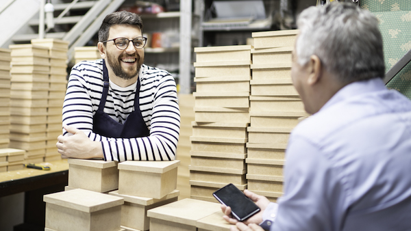 father and son talking cheerfully in storage room while dad looks at mobile phone